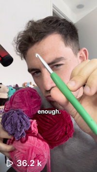 a man is holding a crochet hook in front of a camera