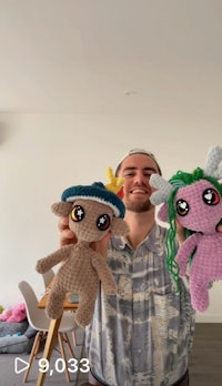 a man holding up three crocheted stuffed animals